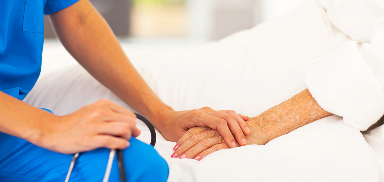 nurse holding a senior's hand