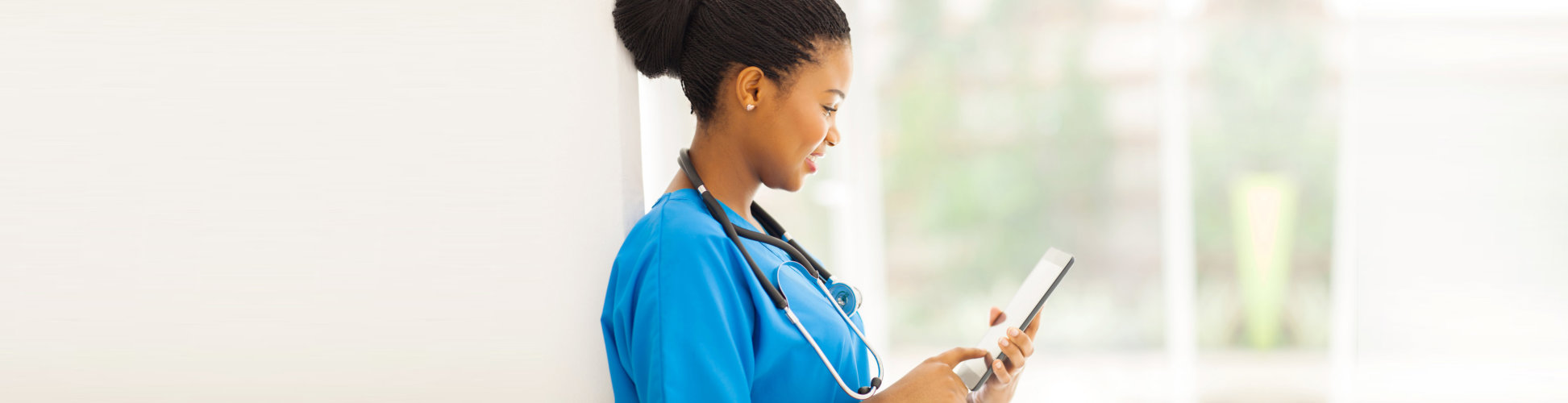 nurse smiling wearing stethoscope using tablet