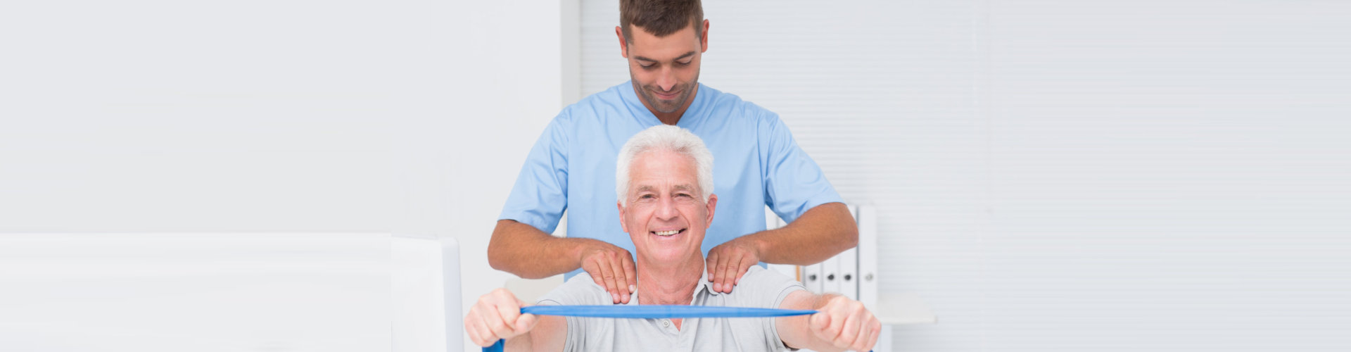 male physiotherapist assisting senior man in exercising with resistance band